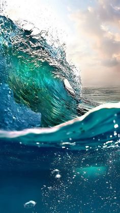 an ocean wave is shown with the sky in the background and water splashing around it