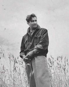 an old photo of a man standing in tall grass