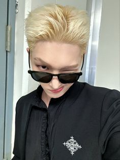 a woman with blonde hair wearing sunglasses and a black shirt is looking at her cell phone