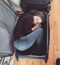 a woman is sitting in an open suitcase