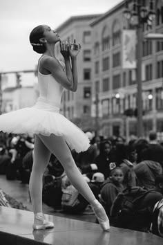 a black and white photo of a ballerina drinking from a water bottle in front of a crowd