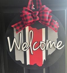 a welcome sign with a red and white checkered bow hanging from the front door