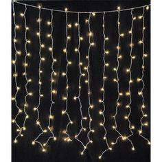 a string of lights hanging from the side of a black wall in front of a window