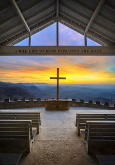 the inside of a church with benches and a cross in front of it at sunset