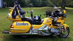 a yellow motorcycle parked on top of a lush green field