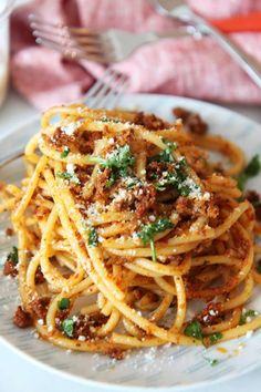 spaghetti with meat sauce and parmesan cheese on a plate next to a fork