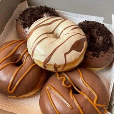 four chocolate covered donuts with white frosting and drizzled on them