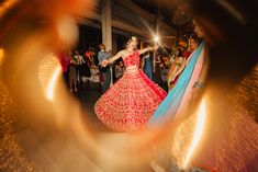 a woman in a red and blue dress is dancing on the dance floor with other people