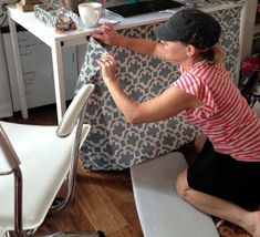 a woman sitting on the floor working on a piece of furniture in her home office