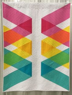 a multicolored quilt hanging on the wall