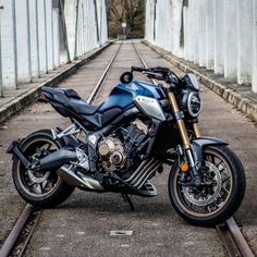 a blue motorcycle parked on the side of train tracks