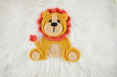 a crocheted lion sitting on top of a white rug