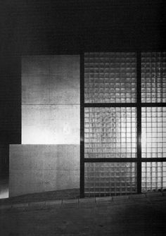 a black and white photo of an empty room with glass blocks on the wall in front of it