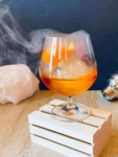 a glass filled with liquid sitting on top of a wooden table next to a stack of coasters