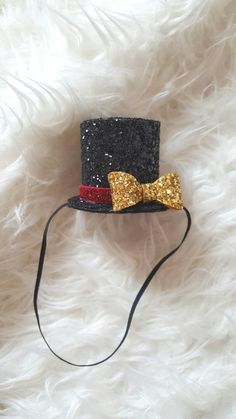 a black hat with a gold bow tie on top of white fluffy furnishing