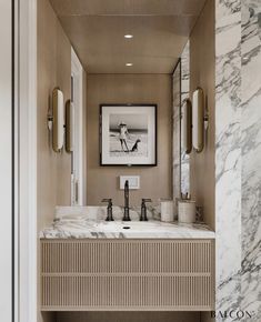 a bathroom with marble counter tops and two sinks in the center, framed art on the wall