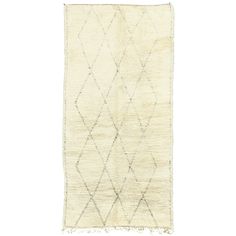 a white rug with diamond shapes on the bottom and fringes at the ends,