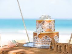 a wedding cake sitting on top of a wooden table next to the ocean and beach