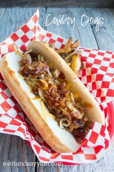 there is a hot dog with onions and mustard on the bun, sitting on a checkered paper plate