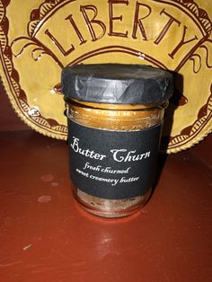 a jar of butter sitting on top of a red table next to a yellow plate