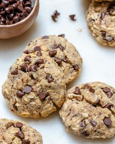 cookies with chocolate chips and oatmeal are on a white surface next to a bowl