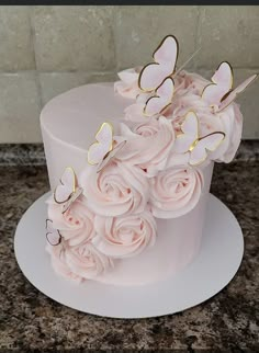 a white cake with pink flowers and butterflies on top