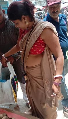 a woman in a sari is preparing food at an outdoor market