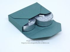 an open green box with two pieces of silver glitter in the middle and one piece missing