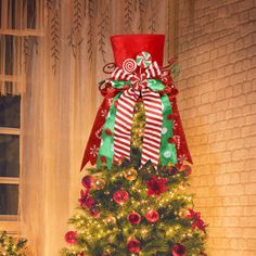 a decorated christmas tree in front of a brick wall with presents on the top and bottom