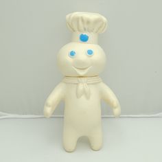 a white plastic toy with blue eyes and a chef's hat on