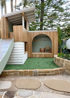 an outdoor play area with a slide and wooden structure in the middle, surrounded by grass