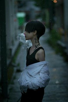 a woman with tattoos on her neck standing in the rain