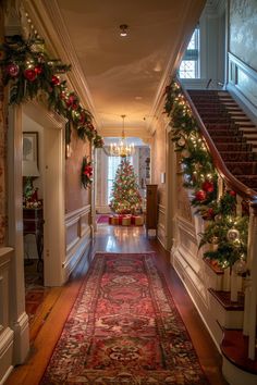 a hallway decorated for christmas with ornaments and garlands on the wall, stairs leading to another room