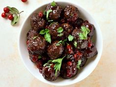 a white bowl filled with meatballs covered in sauce and garnished with parsley