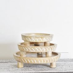 three wooden bowls stacked on top of each other in front of a white wall and rug