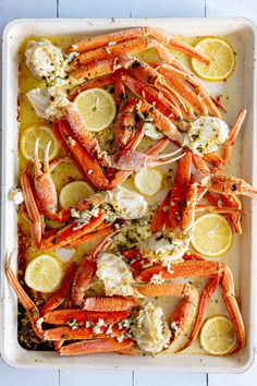 cooked lobsters in a baking dish with lemon wedges and parmesan cheese