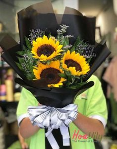 a woman holding a bouquet of sunflowers in her hands