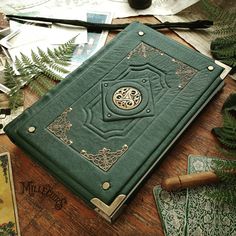 a green book sitting on top of a wooden table next to cards and other items