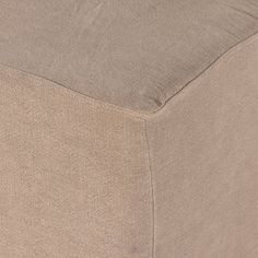 a close up view of the bottom of a footstool with a beige cover