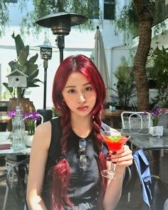 a woman with red hair holding a drink