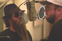 two men with long hair and beards are talking to each other in front of a microphone