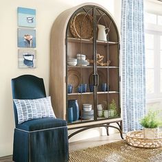 a blue chair sitting in front of a wooden china cabinet