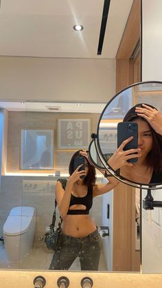 a woman taking a selfie in front of a bathroom mirror with her cell phone