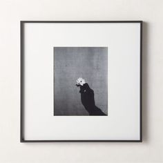 a black and white photo of a person holding a flower in their hand, against a gray background