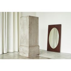 a mirror sitting on the floor next to a tall wooden block with a hole in it