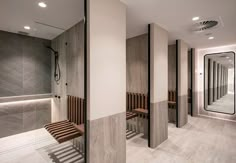 the interior of a modern bathroom with wood benches and mirrors on the wall, along with tile flooring