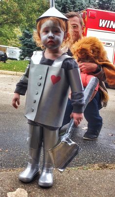 two people in costumes are walking down the street with one person dressed as a robot