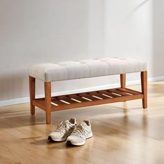 a pair of white shoes sitting on top of a wooden bench next to a wall