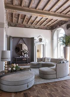 a large living room with wooden floors and white walls, an arched doorway leading to the second floor