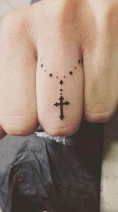 a person's finger with a cross tattoo on it